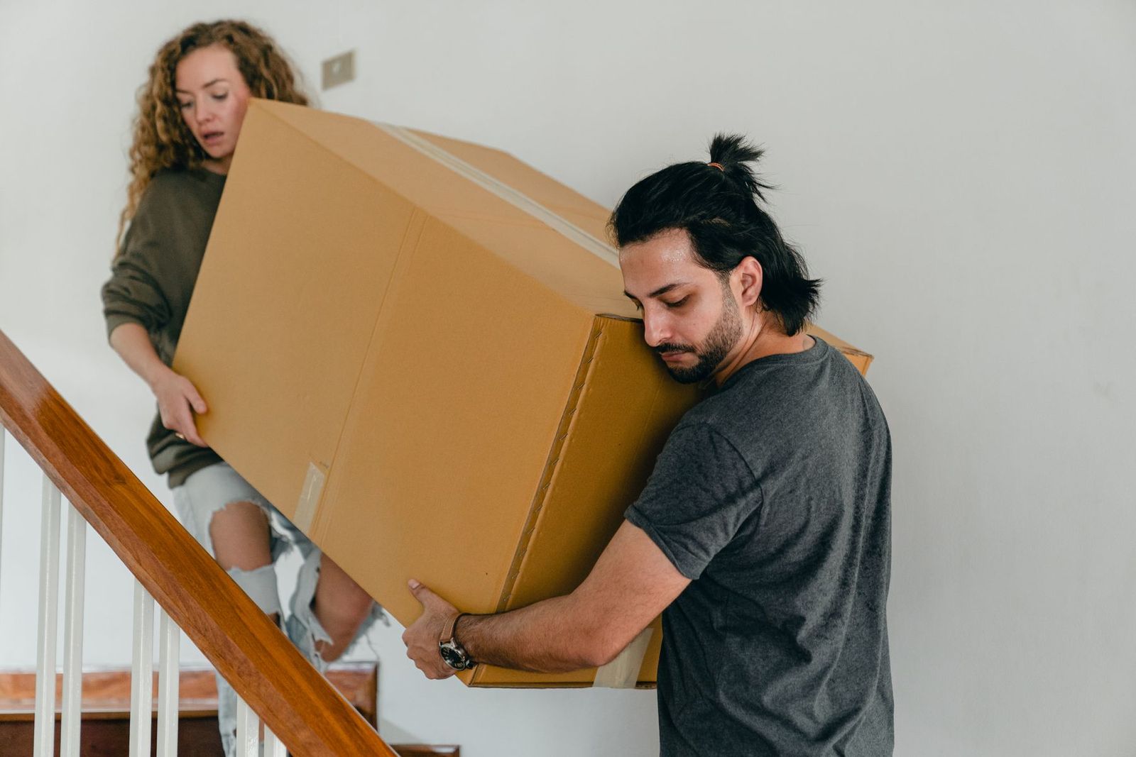 Zwei Personen tragen einen großen Karton die Treppe hinunter